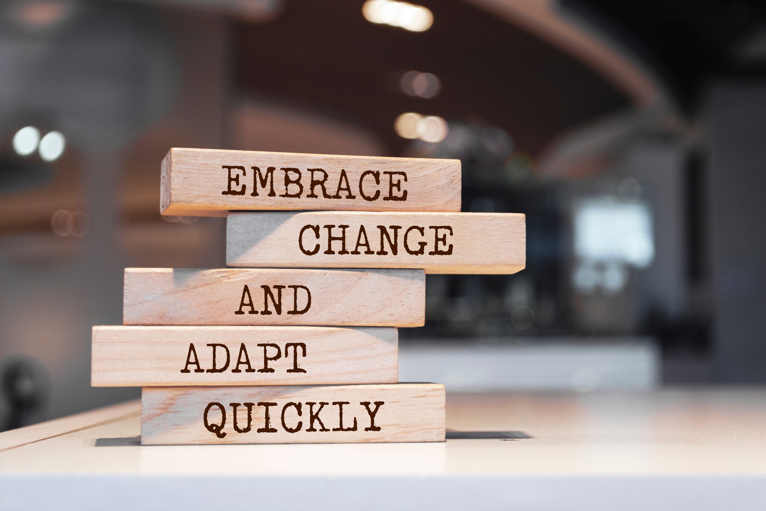 Wooden blocks with a platitude that read "embrace change and adapt quickly."