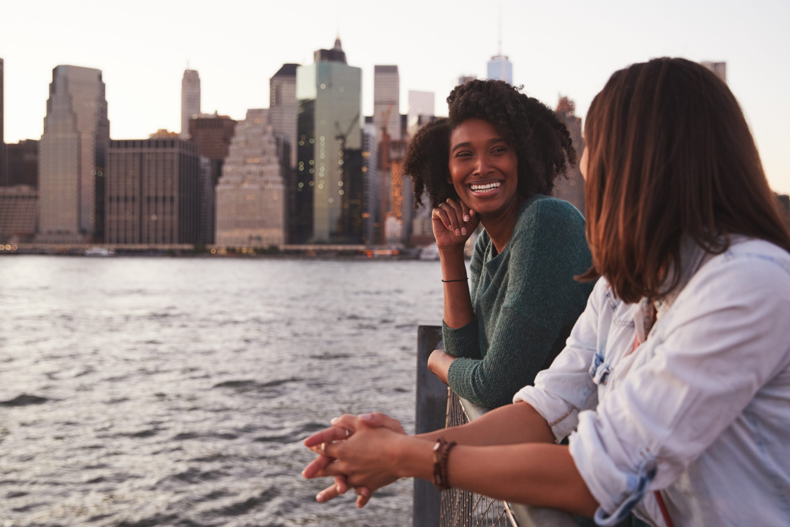 Millennial interracial couple standing on a pier on the Hudson River in NYC with the skyline in the background.